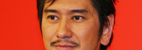 人の名前はわかりません。ジャケットと開襟シャツを身に着けた男性が写っています。