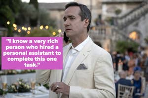 A man in a white suit is talking on a cell phone at an outdoor event, with a table set for dinner and people mingling in the background