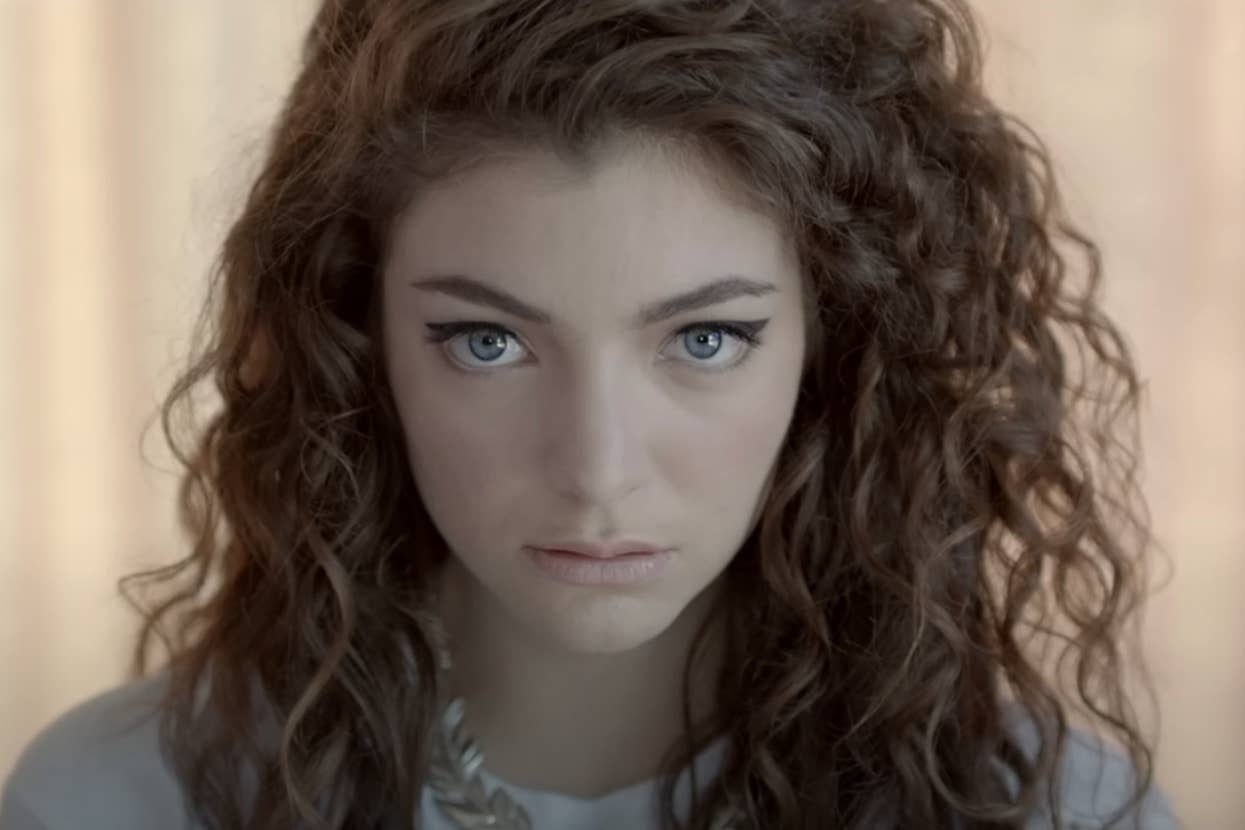 Lorde stares intently ahead, with her curly hair framing her face, in the Royals music video